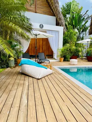a bed on a wooden deck next to a swimming pool at Leeloo Boutique Hotel in Las Terrenas