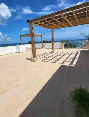 a wooden pergola with a view of the ocean at Elegante Apartamento A 100 mts la playa de los Minos RSJ in Río San Juan