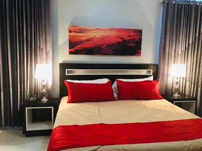 a bedroom with a bed with red pillows and two lamps at Dpravia Hotel SRL in Baní