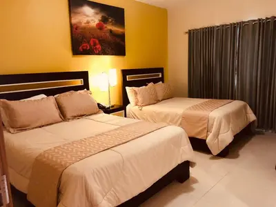 two beds in a hotel room with yellow walls at Dpravia Hotel SRL in Baní