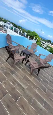 two wooden chairs and a table next to a pool at Residencial Doña Gloria 2 in San Felipe de Puerto Plata
