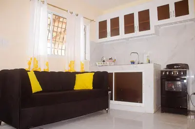 a living room with a black couch and a kitchen at Guest House A&H in Boca Chica