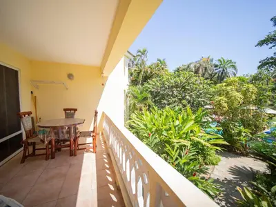 a balcony with a table and chairs and trees at 2br Caribbean Condo In Cabarete Center in Cabarete