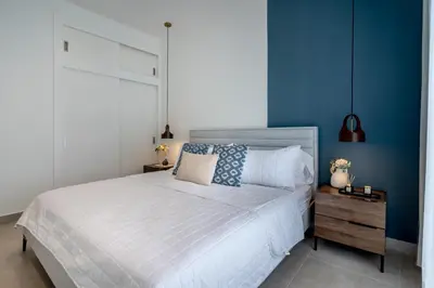 a bedroom with a white bed and a blue wall at Elegant Seaside Villa Steps to Beach & Golf Course in Boca del Soco