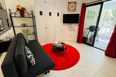 a living room with a black couch and a red rug at Residencial Tropimar Sosua in Sosúa