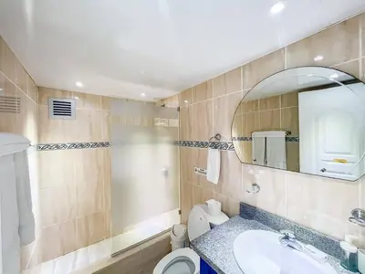 a bathroom with a sink and a toilet and a mirror at Garden Condos 43, Modern Condo In Sosa Center in Sosúa