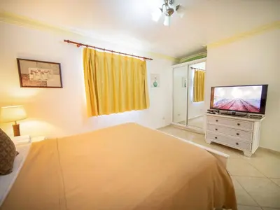 a bedroom with a bed and a flat screen tv at Garden Condos Apt 30 - Lovely 1br Condo W Pool in Sosúa