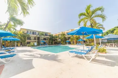 a swimming pool with blue umbrellas and chairs at Garden Condos Apt 30 - Lovely 1br Condo W Pool in Sosúa