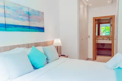 a bedroom with a large white bed with blue pillows at Beach Homes Punta Cana in Punta Cana