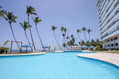 a swimming pool at a resort with palm trees at Xeliter Las Olas Juan Dolio in Guayacanes