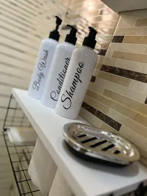 three white shampoo bottles on a shelf in a bathroom at alojamiento en san juan de la maguana in SJM