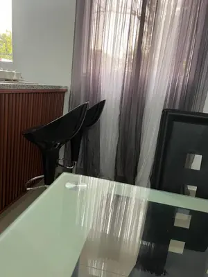 a glass table and two chairs in a room at alojamiento en san juan de la maguana in SJM