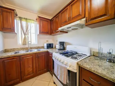 a kitchen with wooden cabinets and a stove top oven at Garden Condos 40, 1br Apt In Sosua Strip Guest Ok in Sosúa