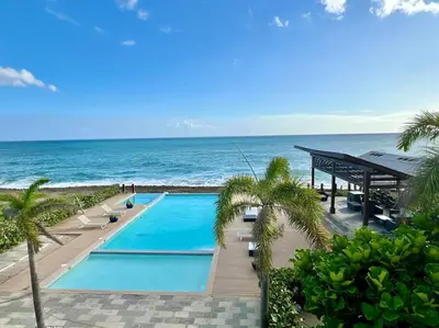 a swimming pool with the ocean in the background at Serenity by the Sea Oceanfront Apartment in San Pedro de Macorís