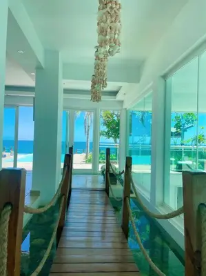 a room with chairs and a chandelier and the ocean at Serenity by the Sea Oceanfront Apartment in San Pedro de Macorís