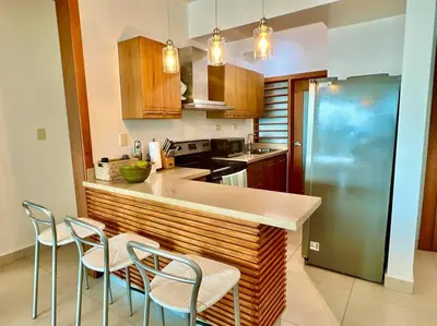 a kitchen with a counter with chairs and a refrigerator at Serenity by the Sea Oceanfront Apartment in San Pedro de Macorís