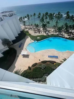 an aerial view of a swimming pool and the ocean at Bueno Paradise Condo In Marbella in Juan Dolio