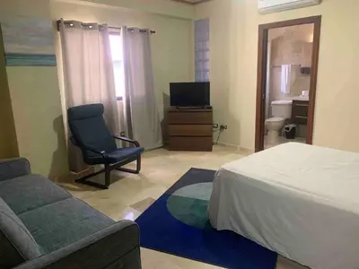 a bedroom with a bed and a chair and a television at Modern Centrical Evaristo Apartment With Tub in Los Prados