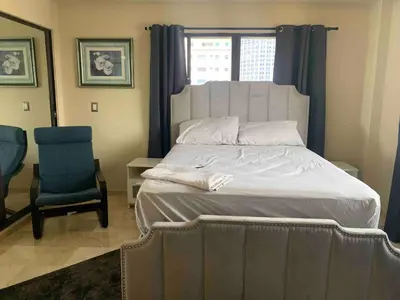 a bedroom with a large bed and a blue chair at Modern Centrical Evaristo Apartment With Tub in Los Prados