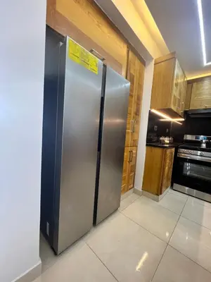a stainless steel refrigerator in a kitchen with wooden cabinets at Ático fantástico in Santiago de los Caballeros