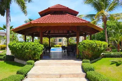 a pavilion with a table and chairs in a garden at Punta Cana 1-Bed Apt Sleeps 4 with Pool & Hot Tub in Punta Cana