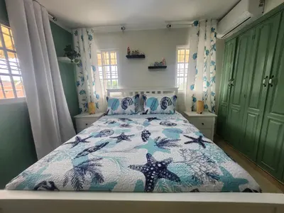 a bedroom with a bed with a blue and white comforter at Penthouse Apartment with Bay and Mountain Views, Rooftop BBQ, AC, Fast WiFi, Near Saladilla Beach, Barahona in Santa Cruz de Barahona