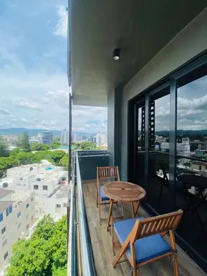 a balcony with two chairs and a wooden table at Condo hotel rialto Recidences in Santiago de los Caballeros