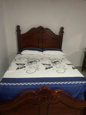 a bed with a wooden headboard and white sheets at villa mariposa in Santo Domingo