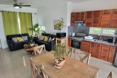 a kitchen and living room with a table and a couch at 2 Bedroom Pool Villa in Gated Encuentro Residences by Palm Hills Real Estate in Cabarete