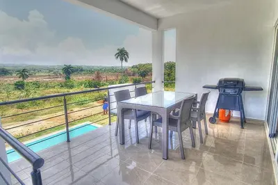 a dining room with a table and chairs on a balcony at 2 Bedroom Pool Villa in Gated Encuentro Residences by Palm Hills Real Estate in Cabarete