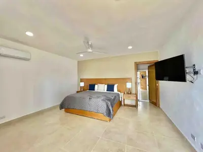 a bedroom with a bed and a flat screen tv at Exclusive Paradise Palms Villa in Sosúa