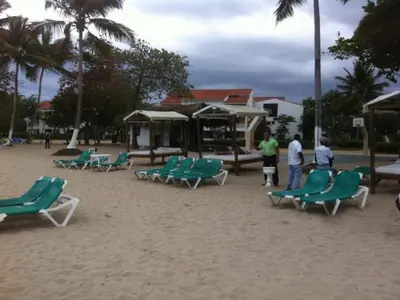 a group of chairs on a sandy beach with people at Celuisma Playa Dorada All Inclusive in Sampiño