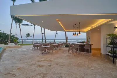 a dining area with tables and chairs and the ocean at Aquarella Sunset Caribbean Beachfront Gataway in La Puntica de Juan Dolio