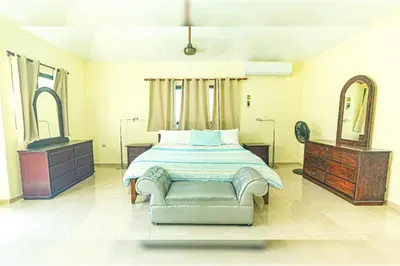 a bedroom with a bed and a chair and a mirror at Villa Infinito Bani's Exclusive Beachside Mansion in Baní
