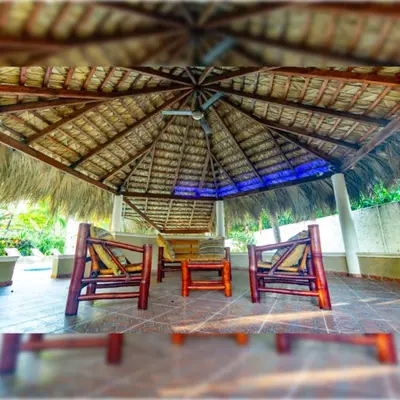 two chairs under a straw umbrella on a patio at Villa Infinito Bani's Exclusive Beachside Mansion in Baní