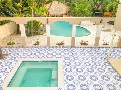 a swimming pool on a tiled floor next to a house at Villa Infinito Bani's Exclusive Beachside Mansion in Baní