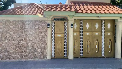 a house with two wooden garage doors and a brick wall at Increible Casa Con Piscina! in Los Frailes