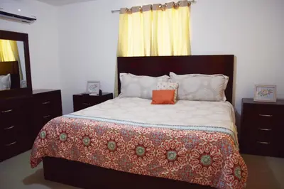 a bedroom with a large bed with an orange pillow on it at Relax in this apartment in Santiago de los Caballeros