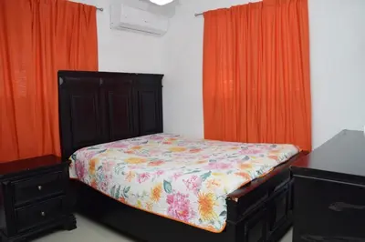 a small bedroom with a bed and orange curtains at Relax in this apartment in Santiago de los Caballeros