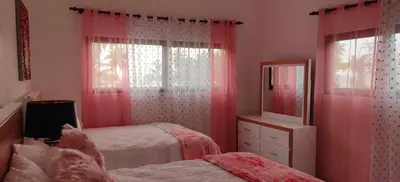 a pink bedroom with two beds and a mirror at Villa Dario in Nagua