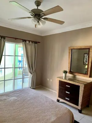 a bedroom with a ceiling fan and a television at Palm Suites E-6-two-level apartment with a view of the pool in Punta Cana