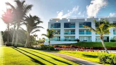 a large white building with palm trees in front of it at Cana Rock Condos in Punta Cana