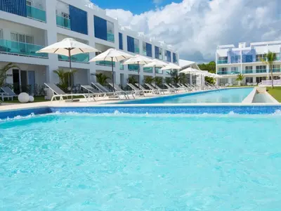 a swimming pool with chairs and umbrellas in front of a hotel at Cana Rock Condos in Punta Cana