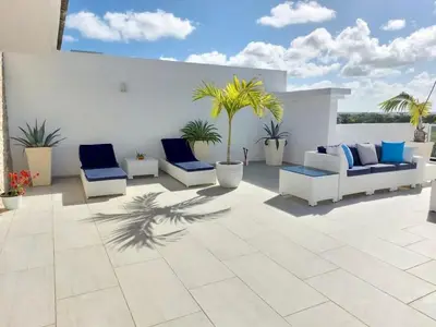 a patio with blue and white furniture and palm trees at Luxury Gateaway Penthouse in front of Hard Rock in Punta Cana