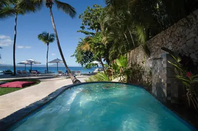 a swimming pool next to a beach with palm trees at Select Sosua Adults Only, Trademark by Wyndham All Inclusive in Sosúa
