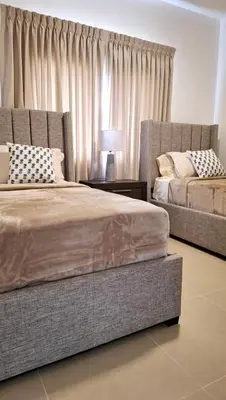 a bedroom with two beds and a window with curtains at Atlantic Paradise Cabrera in Arroyo Azul