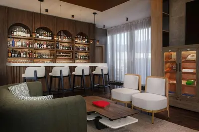 a bar with white chairs and a table in a room at AC Hotel by Marriott Santiago de los Caballeros in Santiago de los Caballeros