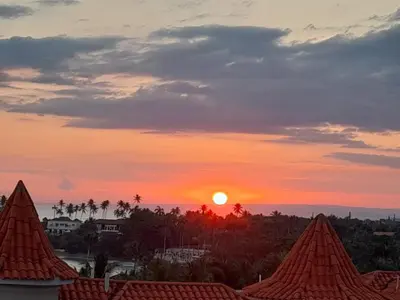 a sunset from the roof of a building at 1BR Suite at Villa Costa Verde near Playa Cofresi, Puerto Plata, with a pool, balcony and a rooftop terrace in San Felipe de Puerto Plata