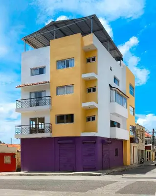 a yellow and white building with purple doors at Apartahotel Señorial in Higuey