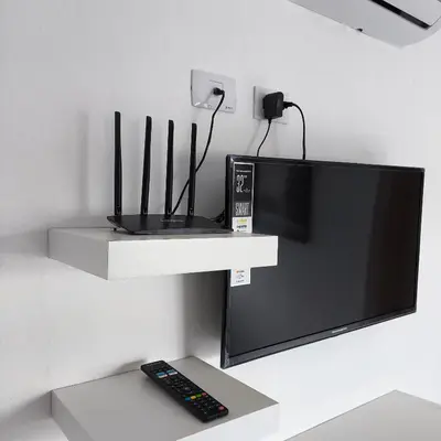 a tv on a wall with a remote control at Apartahotel Señorial in Higuey